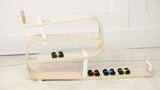 Wooden shelf with colorful dumbbells on a light wooden floor.