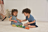 Two children playing with colorful wooden toys on a light-colored floor.