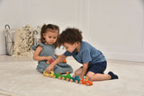 Two children playing with toy cars on a light-colored floor.