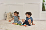 Two children playing with colorful toy cars on a light-colored floor.
