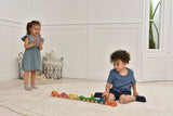 Two children playing with toy cars on a light-colored floor.