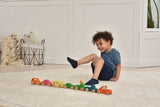 Child playing with a colorful wooden toy train on a light wood floor.