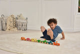 Child playing with a colorful toy train on a light wooden floor.