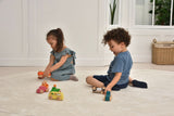 Two children playing with toys on a light wooden floor.