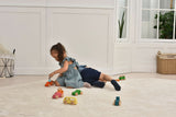 Child playing with toy cars on a light wooden floor.
