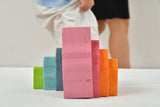 Colorful wooden blocks stacked on a white surface with a blurred person in the background.