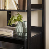 Bookshelf with books and a green vase on a neutral background