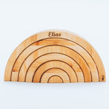 Wooden rainbow-shaped toy with 'Elias' engraved on a white background