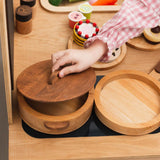 Child playing with wooden toy kitchen items on a wooden surface