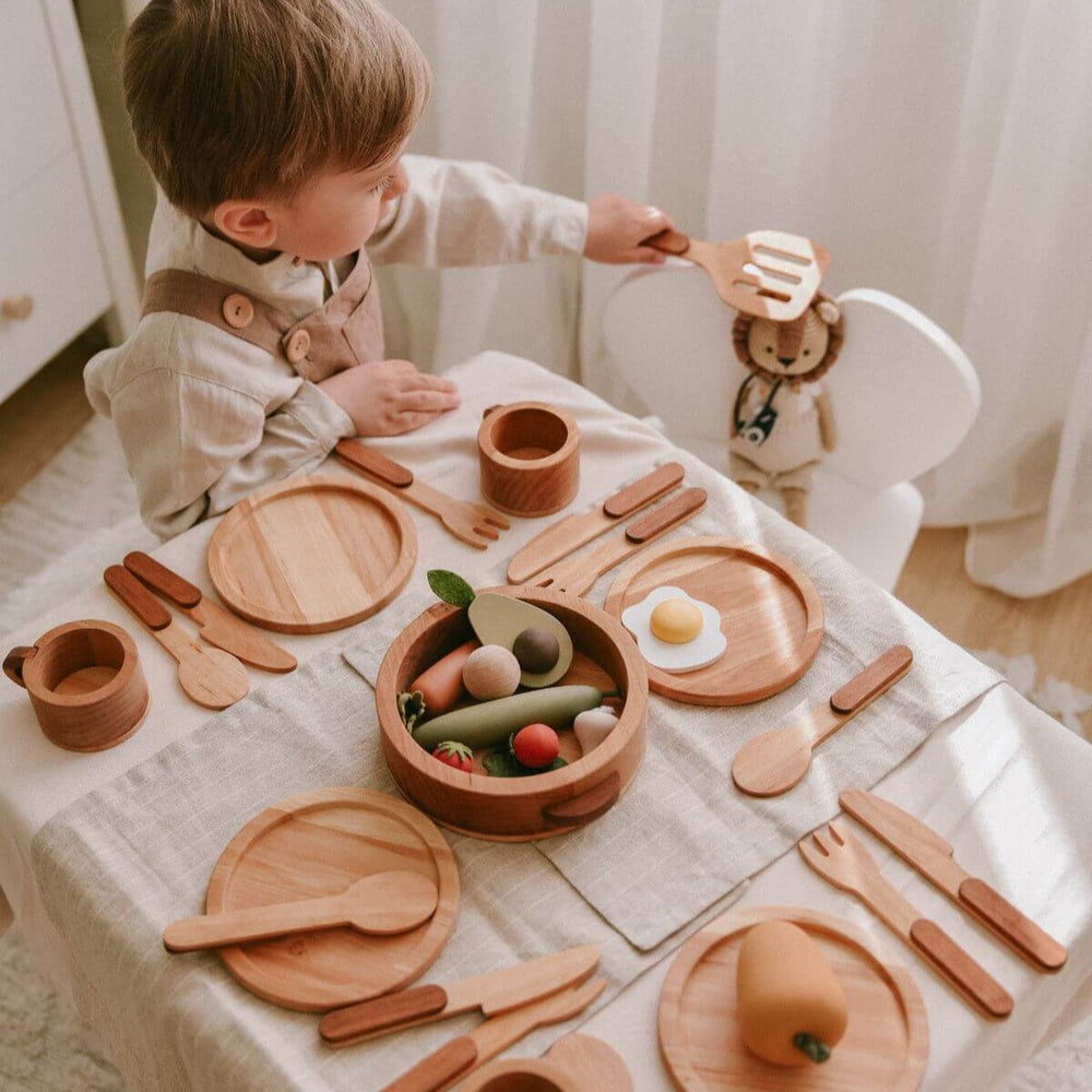 Child playing with wooden toys on a tablecloth-covered table.