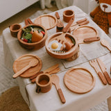 Wooden toy kitchen set on a tablecloth with a teddy bear in the background