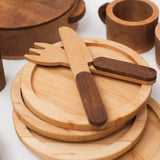 Wooden cutlery set on wooden plates with a white background