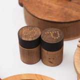 Two wooden salt shakers with black bands on a white surface.